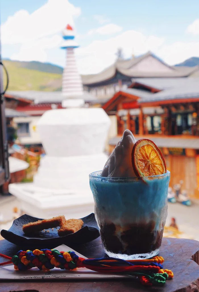 This cup of coffee ☕️ is called "The Tears of Kawagarbo". The deep coffee base resembles the night sky over Tibet, the creamy coconut 🥥 milk flows like glacial meltwater, and the blue velvet syrup swirls like sacred lake ripples. But the real masterpiece is the edible snow-capped mountain 🏔️ on top, take a bite, and the divine energy of Meri Snow Mountain surges straight to your soul! 
🤩 Find it in the Dukezong Ancient Town of Shangri-La, Yunnan!